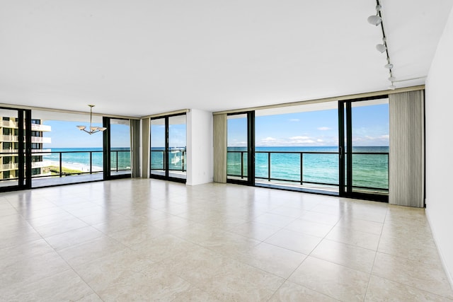 unfurnished room featuring a water view, floor to ceiling windows, an inviting chandelier, and light tile patterned floors