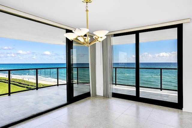 interior space featuring a water view, expansive windows, a view of the beach, and a chandelier