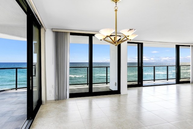 spare room featuring expansive windows, a water view, a healthy amount of sunlight, and a notable chandelier