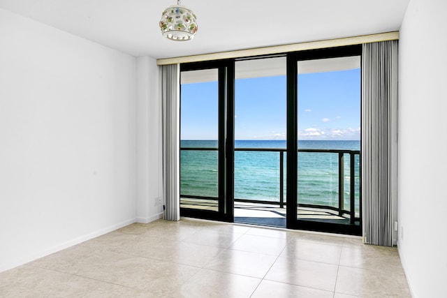 tiled empty room featuring expansive windows and a water view