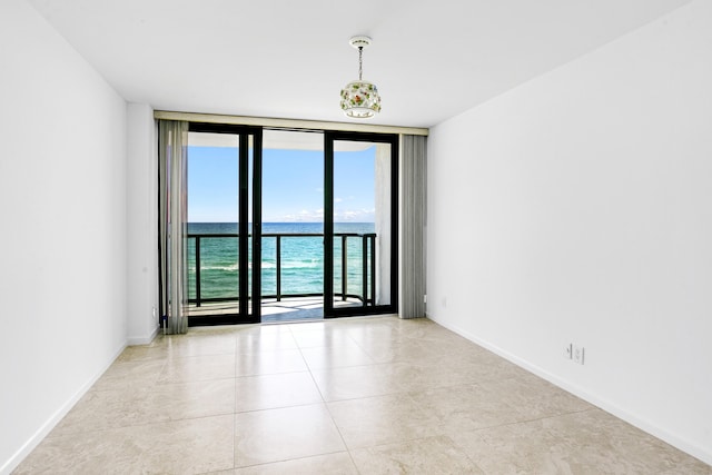 empty room with a water view, floor to ceiling windows, and light tile patterned flooring