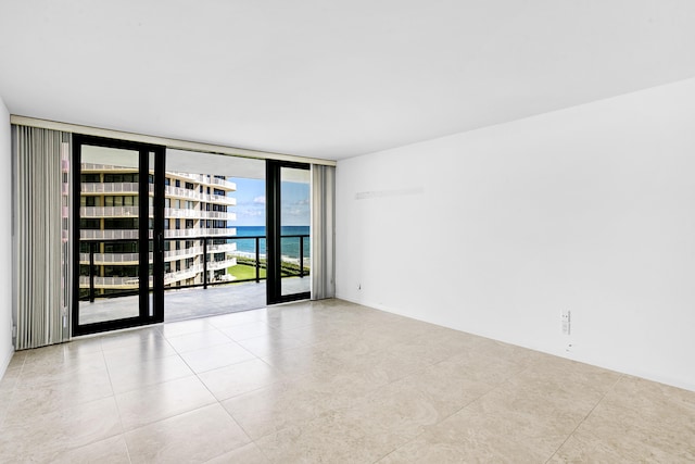 unfurnished room featuring a water view and a wall of windows