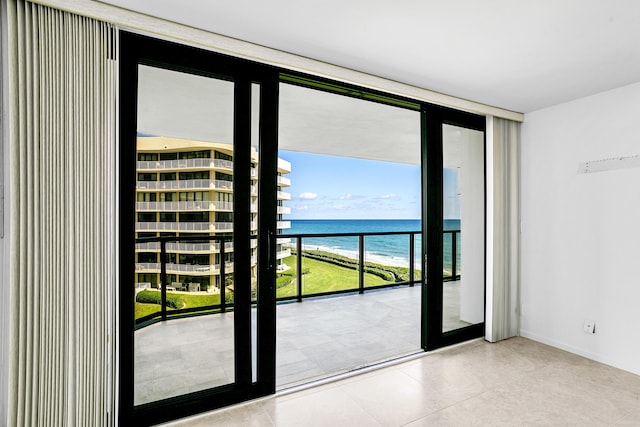 doorway with a view of the beach, floor to ceiling windows, and a water view