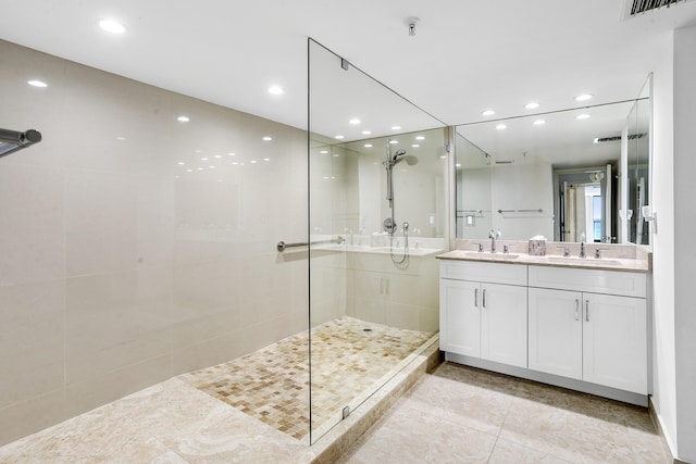 bathroom with tile patterned flooring, vanity, and a tile shower