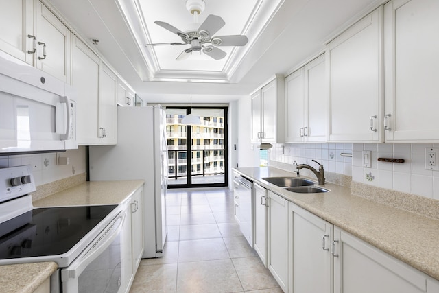 kitchen with white cabinetry, sink, decorative backsplash, a tray ceiling, and white appliances