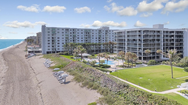 view of building exterior with a water view, a community pool, and a view of the beach