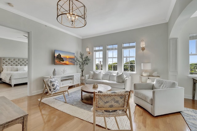 living room with ornamental molding, plenty of natural light, a chandelier, and light wood-type flooring