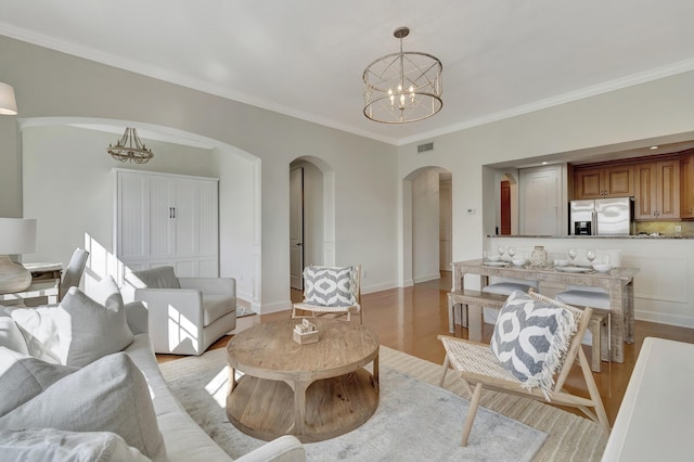 living room with ornamental molding, a chandelier, and light wood-type flooring