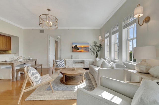 living room with a notable chandelier, ornamental molding, and light wood-type flooring