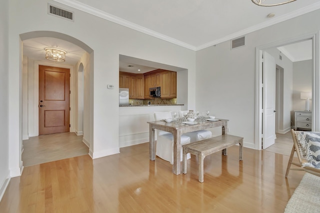 dining area with ornamental molding and light wood-type flooring