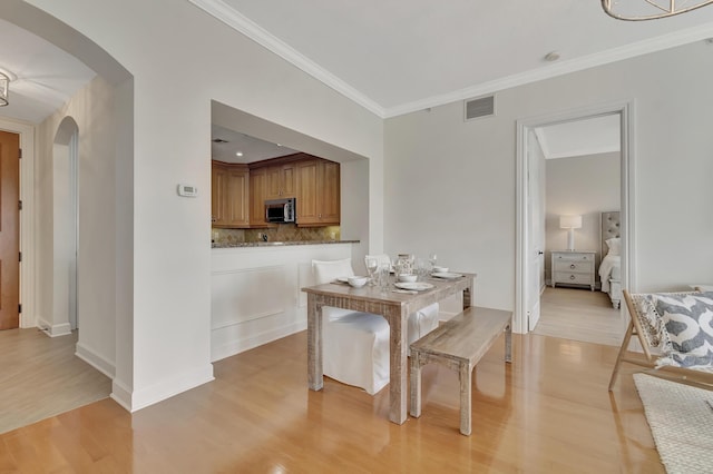 dining space featuring crown molding and light hardwood / wood-style flooring