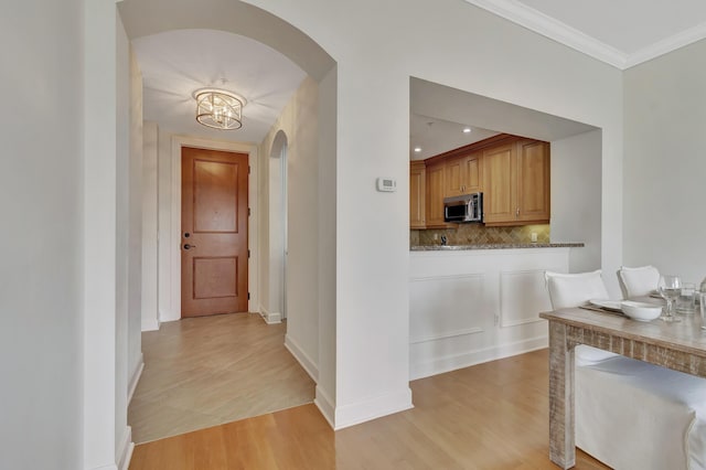 hallway featuring an inviting chandelier, crown molding, and light hardwood / wood-style floors