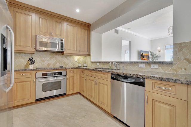 kitchen featuring sink, decorative backsplash, stone counters, and appliances with stainless steel finishes