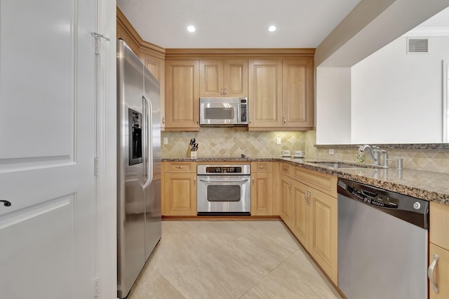 kitchen featuring light brown cabinetry, tasteful backsplash, sink, stainless steel appliances, and light stone countertops