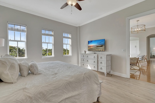 bedroom featuring crown molding, ceiling fan with notable chandelier, and light wood-type flooring