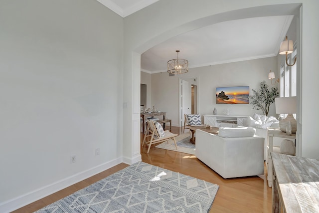 living room featuring crown molding, a chandelier, and light wood-type flooring