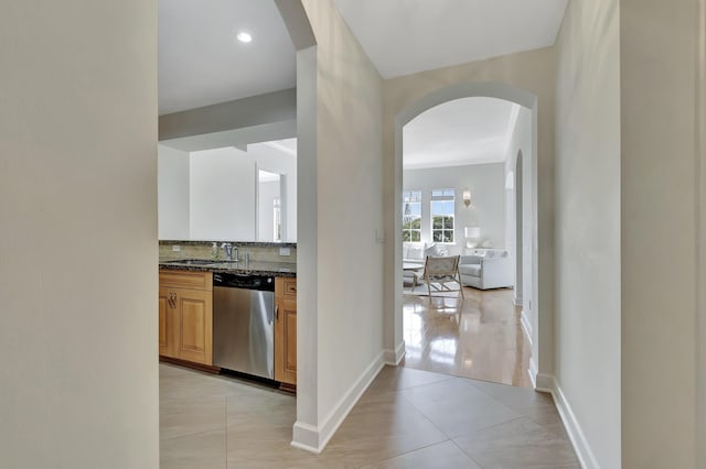 hallway featuring crown molding, sink, and light tile patterned floors