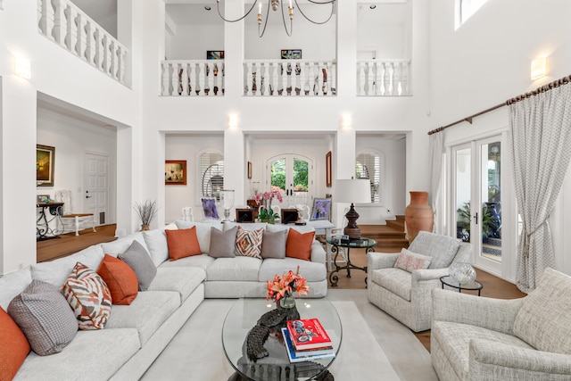 living room with a notable chandelier, french doors, and light wood-type flooring