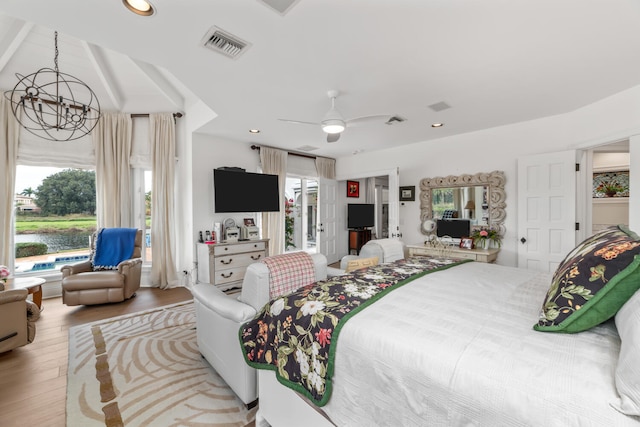 bedroom with multiple windows, ceiling fan with notable chandelier, a walk in closet, and light wood-type flooring