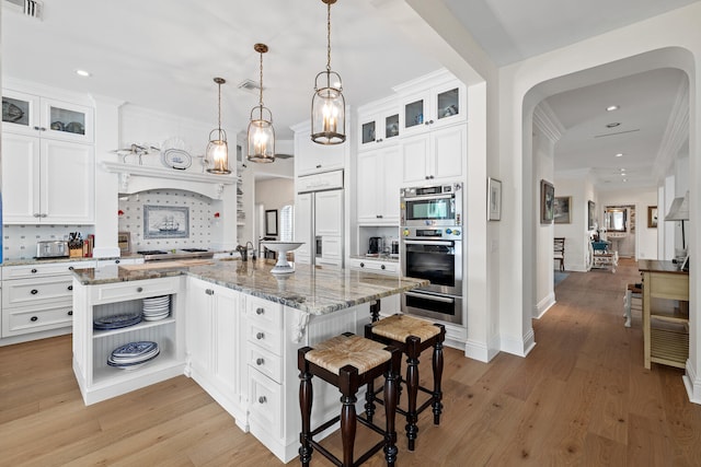 kitchen featuring white cabinetry, dark stone counters, a kitchen island with sink, and pendant lighting