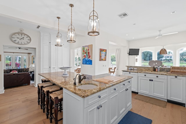 kitchen with white cabinetry, ceiling fan, sink, and a center island with sink