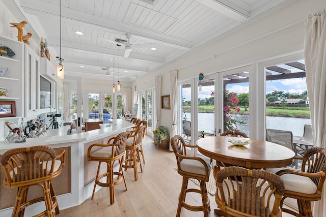 dining space with light hardwood / wood-style floors, french doors, beamed ceiling, and a water view