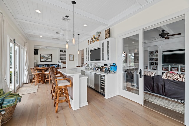 kitchen featuring white cabinetry, decorative light fixtures, beam ceiling, and a breakfast bar area