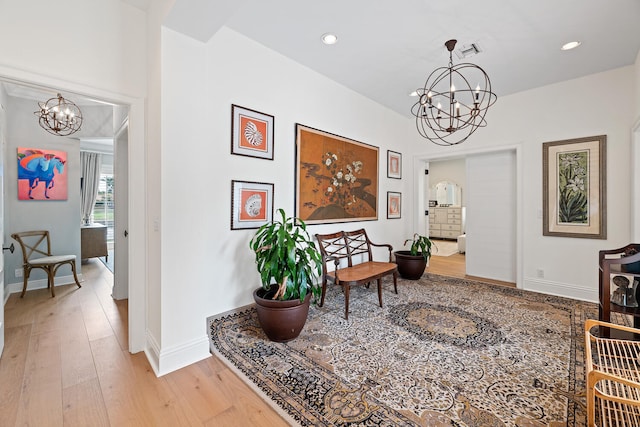 hallway with an inviting chandelier and light wood-type flooring