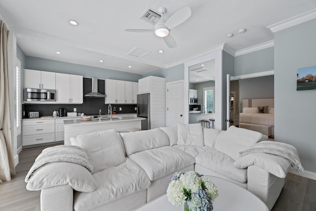 living room with crown molding, sink, ceiling fan, and light hardwood / wood-style flooring