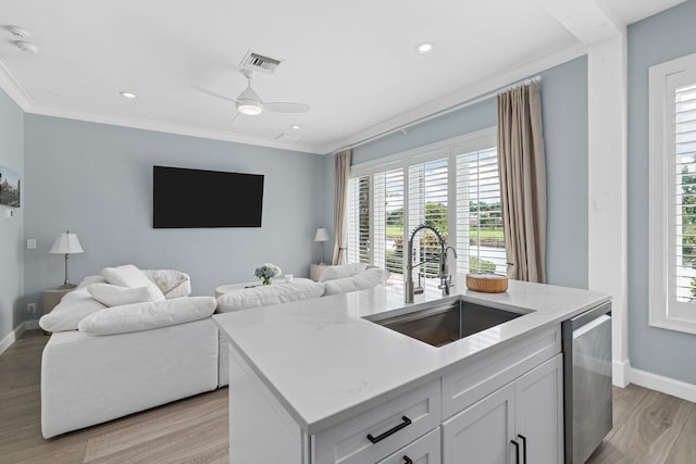 kitchen featuring sink, white cabinetry, stainless steel dishwasher, ornamental molding, and an island with sink