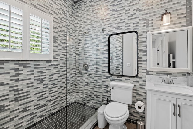 bathroom with toilet, tile walls, a tile shower, vanity, and decorative backsplash