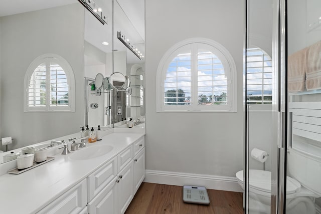 bathroom featuring hardwood / wood-style flooring, vanity, toilet, and a shower with door