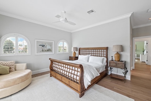 bedroom featuring multiple windows, hardwood / wood-style flooring, and ornamental molding