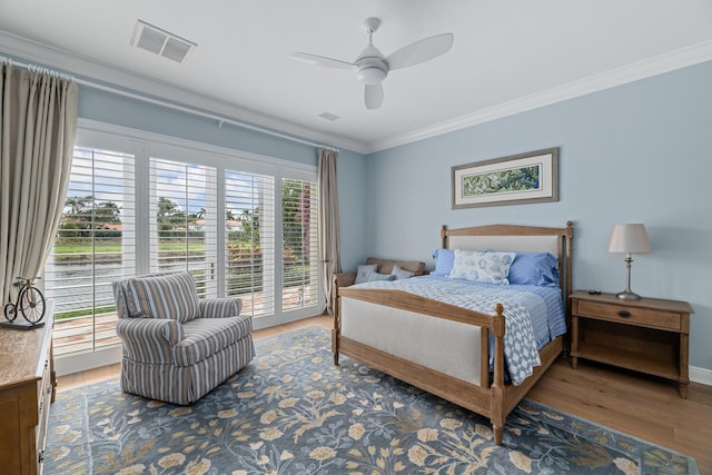 bedroom with ornamental molding, wood-type flooring, access to exterior, and multiple windows