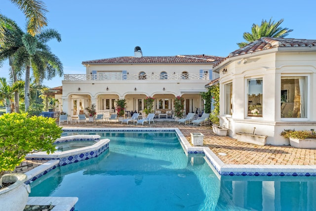 back of house featuring a swimming pool with hot tub and a patio