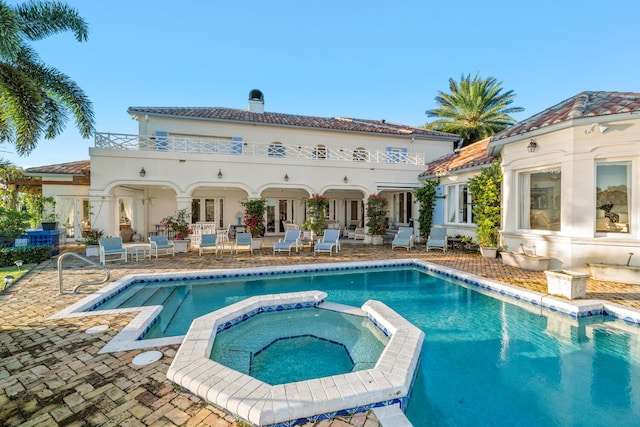 back of property featuring a swimming pool with hot tub and a patio area