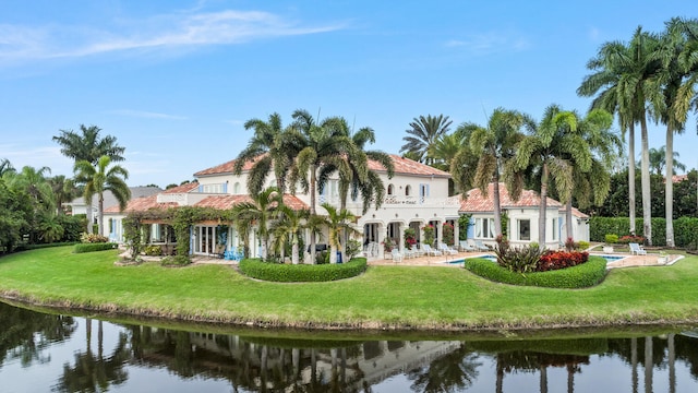 back of property featuring a water view and a lawn