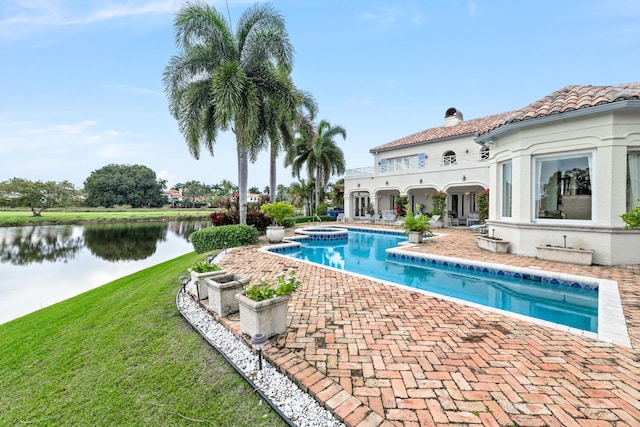 view of pool featuring a patio, a water view, an in ground hot tub, and a lawn