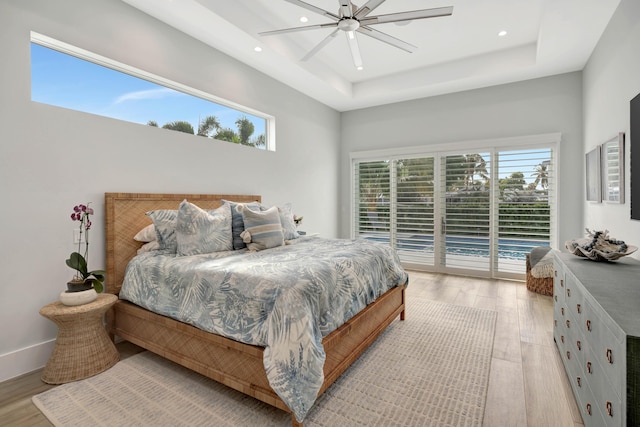 bedroom with a raised ceiling, access to exterior, and light hardwood / wood-style floors