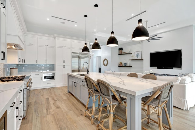 kitchen with white cabinets, a kitchen bar, high end appliances, light stone countertops, and a spacious island