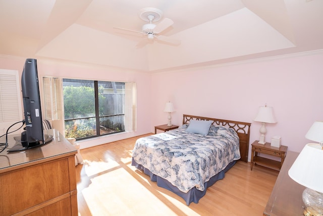 bedroom with hardwood / wood-style flooring, a raised ceiling, and ceiling fan