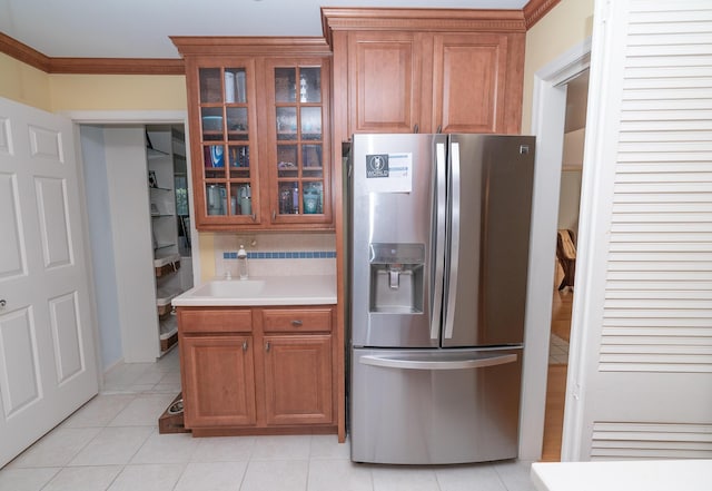 kitchen with ornamental molding, sink, stainless steel fridge with ice dispenser, and light tile patterned floors