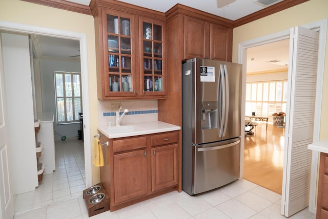 kitchen featuring stainless steel refrigerator with ice dispenser, sink, light tile patterned flooring, and ornamental molding