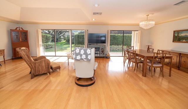 living room featuring a healthy amount of sunlight, a chandelier, and light wood-type flooring