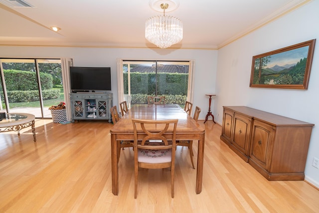 dining space featuring a notable chandelier, ornamental molding, and light wood-type flooring