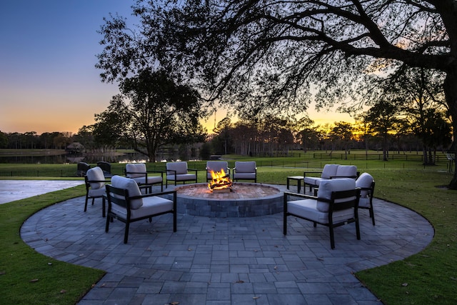 patio terrace at dusk with a fire pit and a lawn