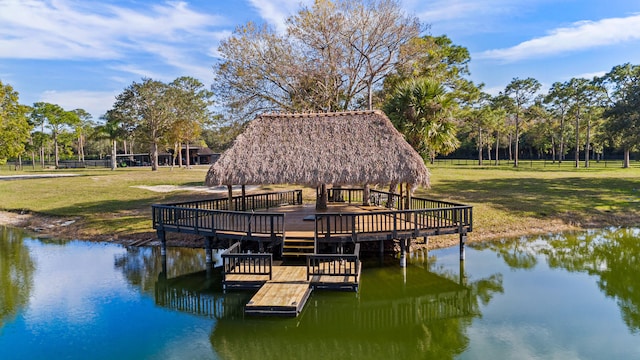 dock area featuring a gazebo, a water view, and a lawn