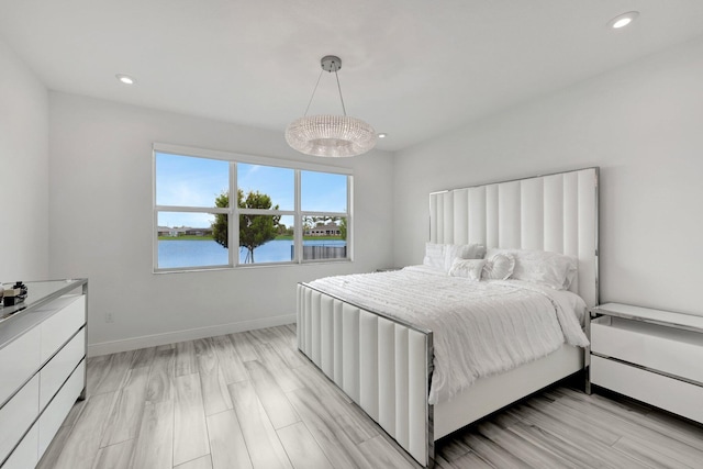 bedroom with a water view and light hardwood / wood-style floors