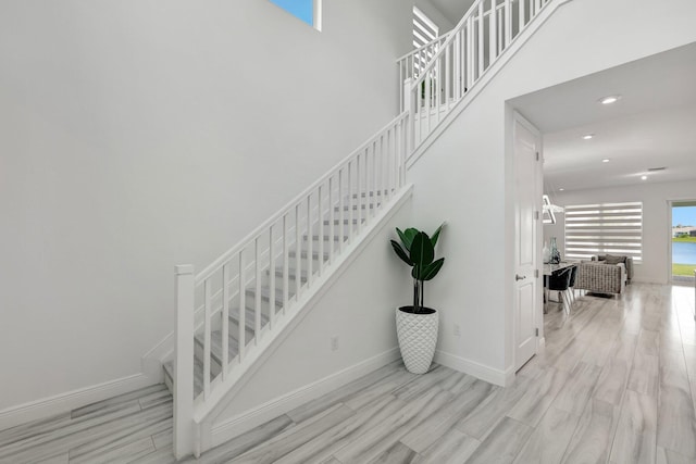 stairs with a high ceiling and wood-type flooring