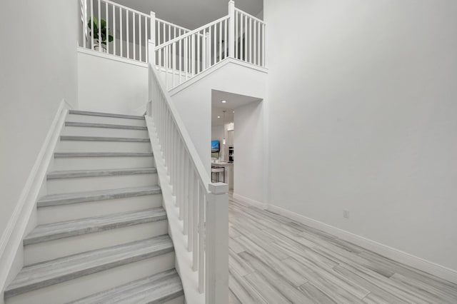 staircase featuring hardwood / wood-style floors and a high ceiling